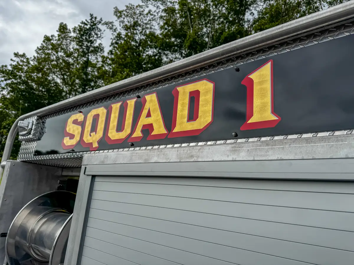 Rear body nameplate close-up mounted on diamond-plate panel.